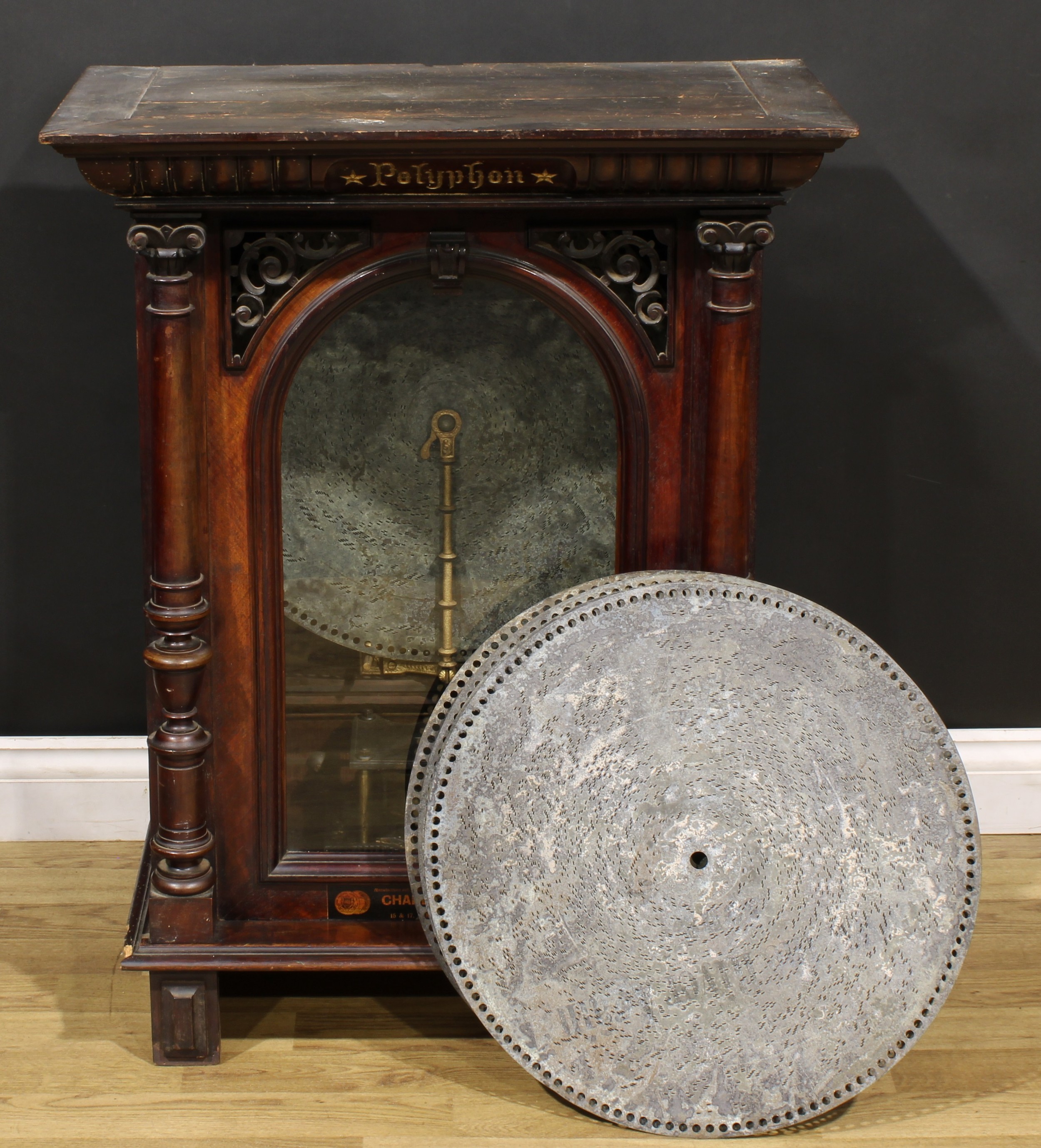 A 19th century coin operated penny-in-the-slot polyphon, the vertical movement playing 50cm discs, retailers label for H. Peters & Co, London and Charles McCann, 15 & 17 Osmaston Road, Derby, 90cm high, 69cm wide, 39.5cm deep, c.1890