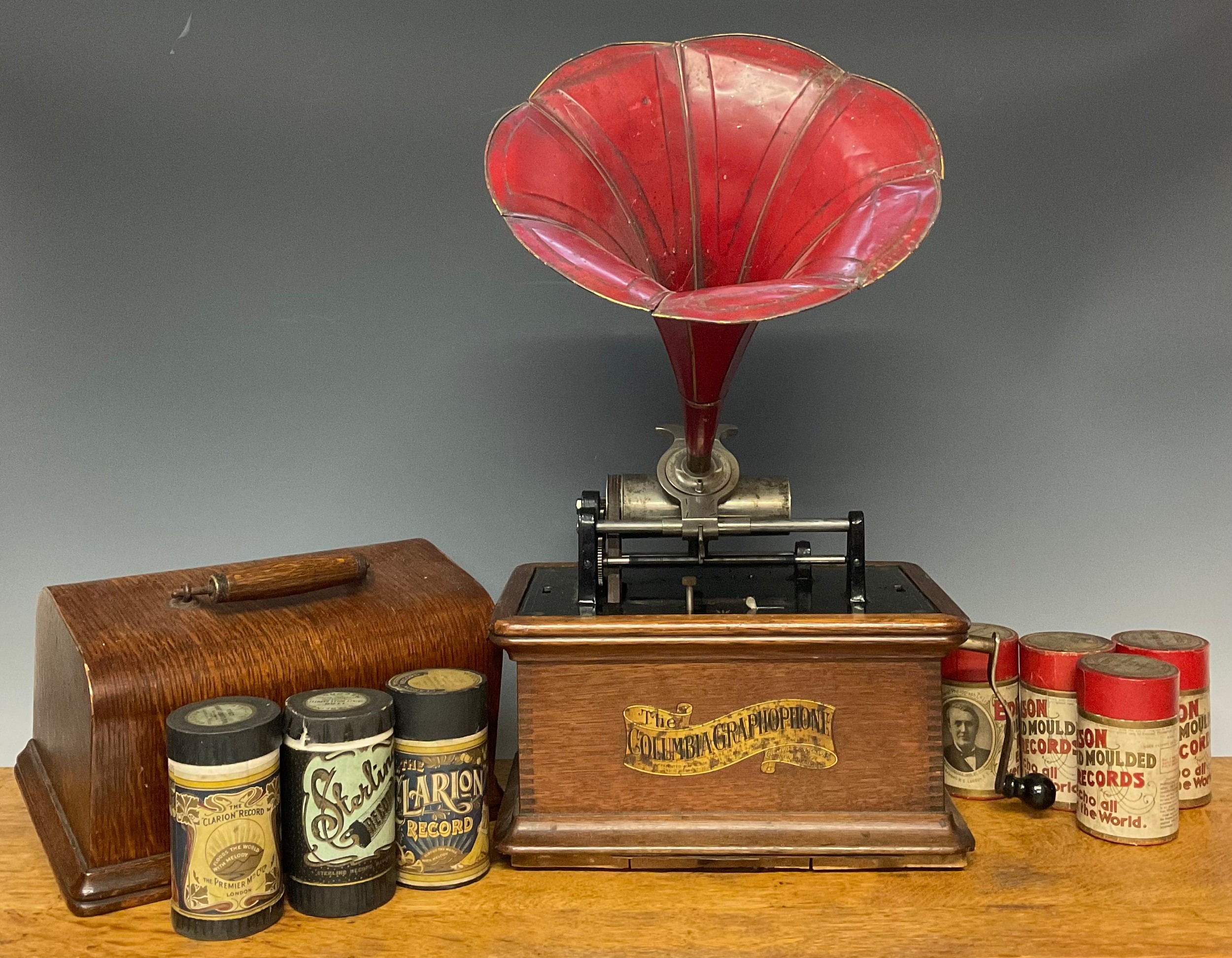 An early 20th century phonograph, The Columbia Gramophone, red painted tin horn, oak case, 31cm wide; a collection of wax phonograph cylinders, mostly Edison Gold Moulded Recorders and Clarion Records, cardboard tubes (approx 24)